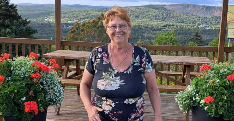 Woman with red hair and black floral shirt. 