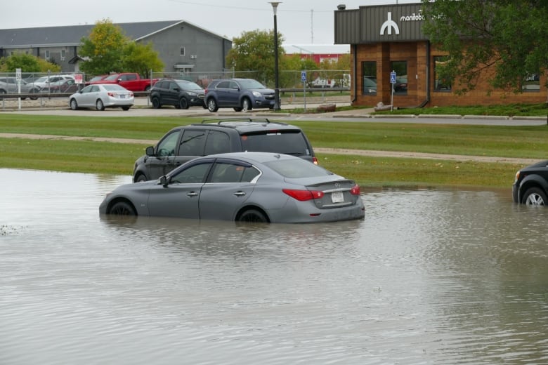 Car are surrounded by water in a flooded street.  