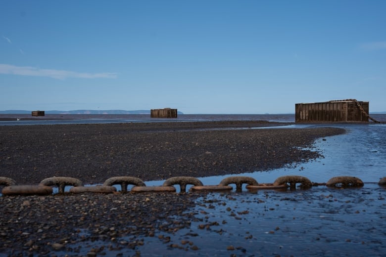 large chain on wet ground with three large containers behind it.