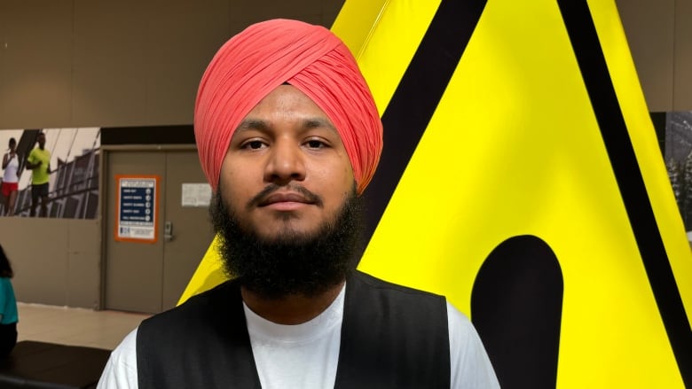 A brown man wearing a pink turban.