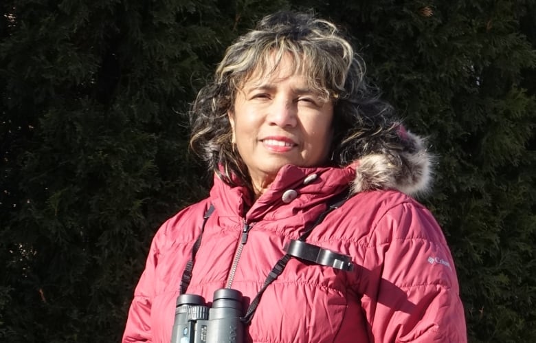 A portrait of a person outdoors wearing a winter coat and binoculars. 