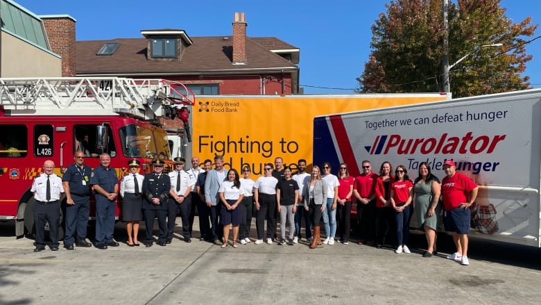 Representatives from the Daily Bread food bank, Toronto Fire Services and Purolator pose for a photo at the launch of the charity's annual Thanksgiving drive.