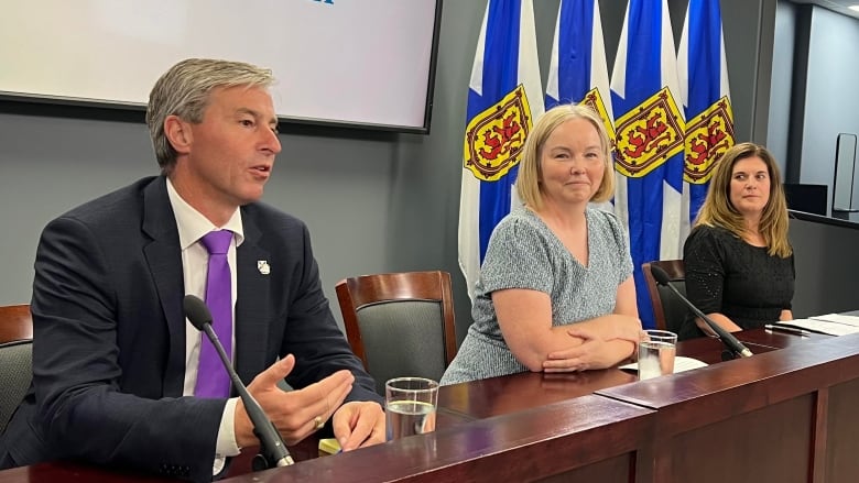 Three people seated in front of microphones.