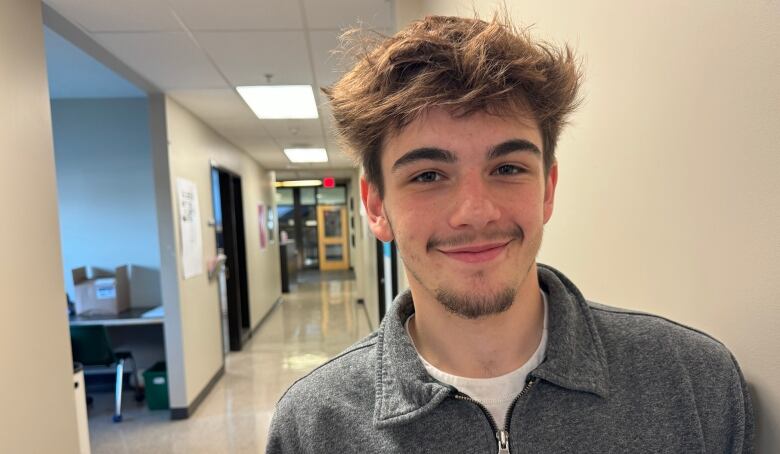 A young man with a beard smiles for the camera