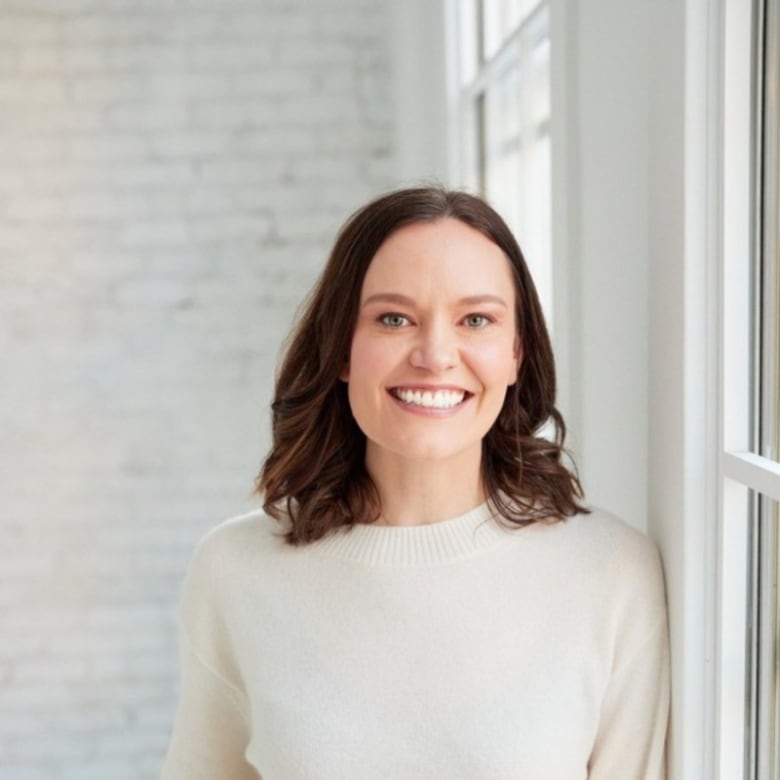 A woman smiles against a white background.