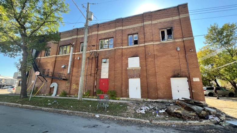 A brick building with a burned mattress laying outside 