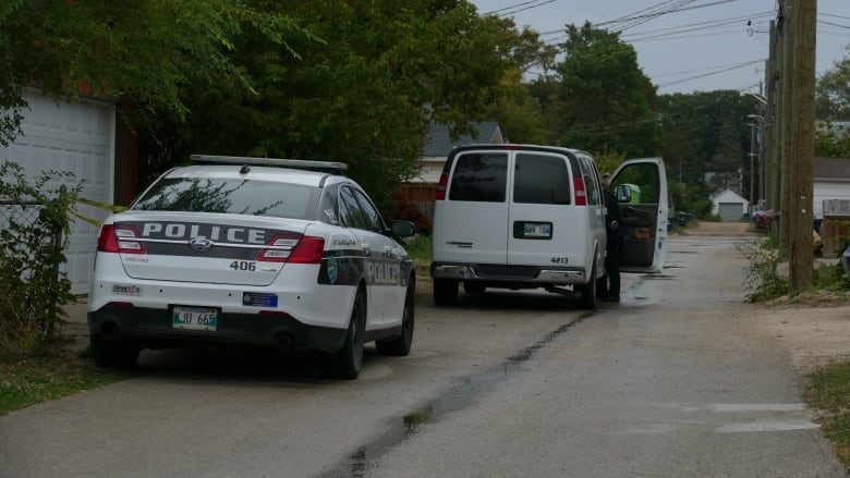 Two police cars are on a back alleyway.