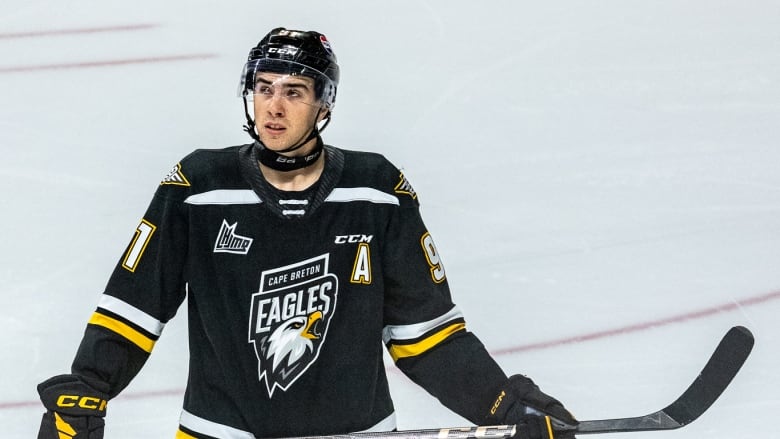 Hockey player on ice in black and yellow jersey and helmet.