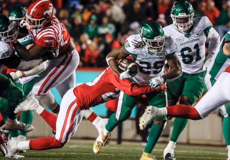 Ryquell Armstead is busting through a group of calgary players while holding the ball