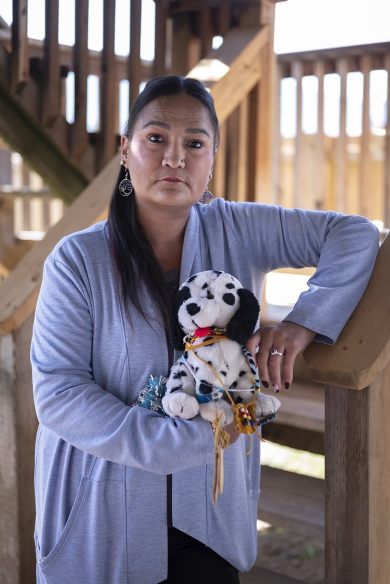 An Indigenous woman holds a stuffed dog toy.