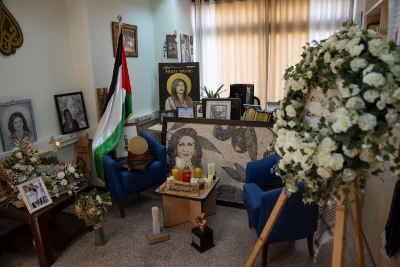 An office is decorated with memorial items including portraits of a woman, flowers and candles.