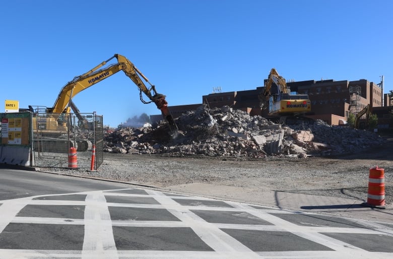 Construction equipment moves rubble from a demolished parking garage.