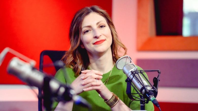 Portrait of a woman sitting at a mic in a radio studio