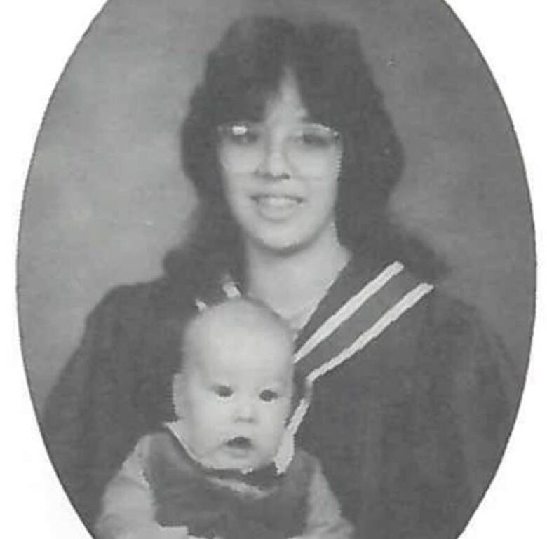 A graduation picture of a girl holding a child.