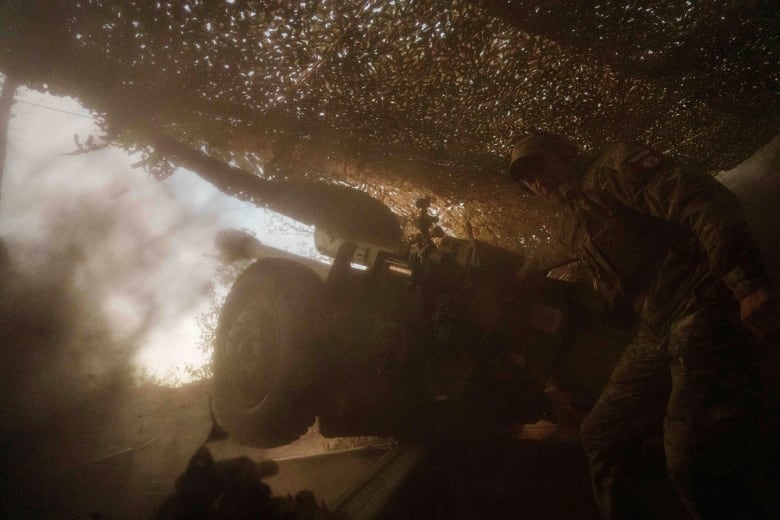 A Ukrainian soldier stands near an artillery cannon being fired toward Russian positions near Toretsk in Ukraine's Donetsk region.