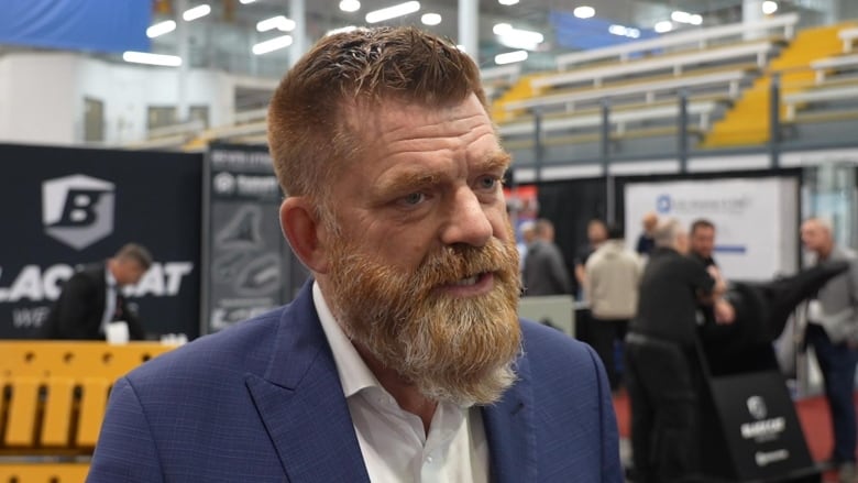 Middle-aged man with big, red, greying beard, dressed in a suit.