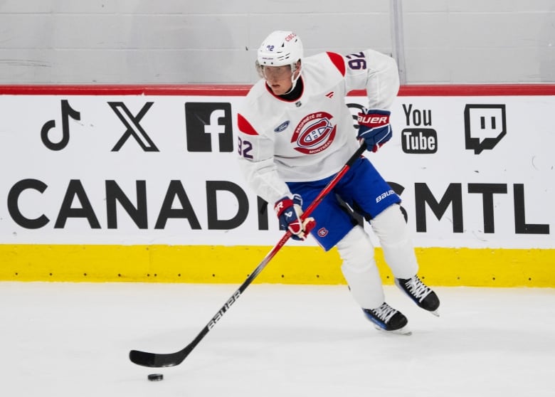 A male ice hockey player wearing number 92 skates with the puck during training camp.