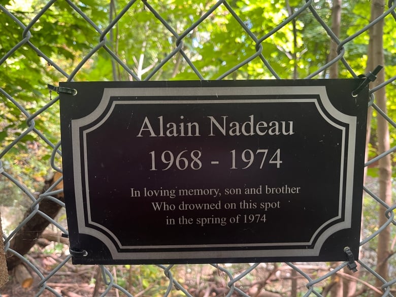 A memorial plaque on a fence reading, 