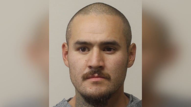 A mugshot of a 34-year-old man with a shaved head.