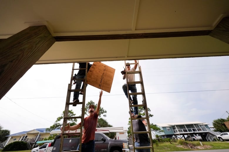 Men climb ladders with wooden panels