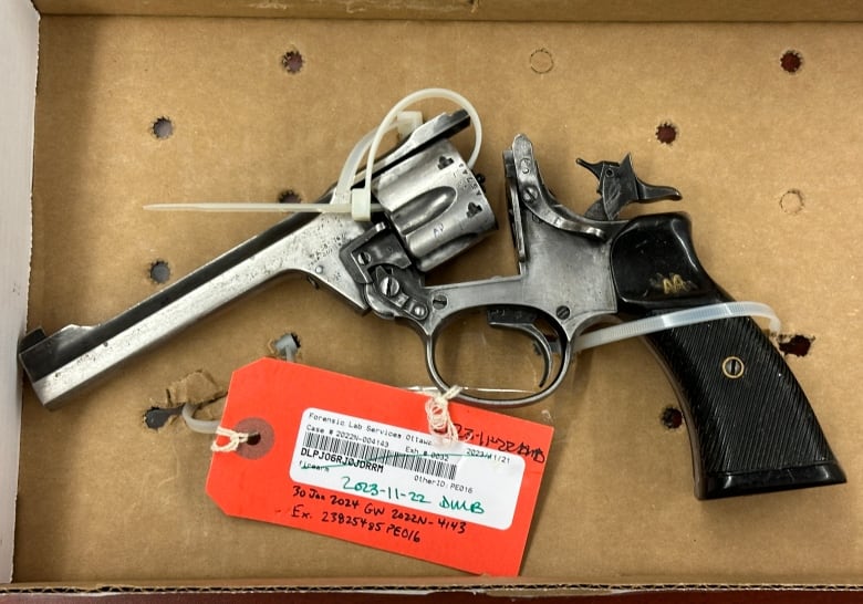 A revolver zip-tied to a box with an orange tag attached. 