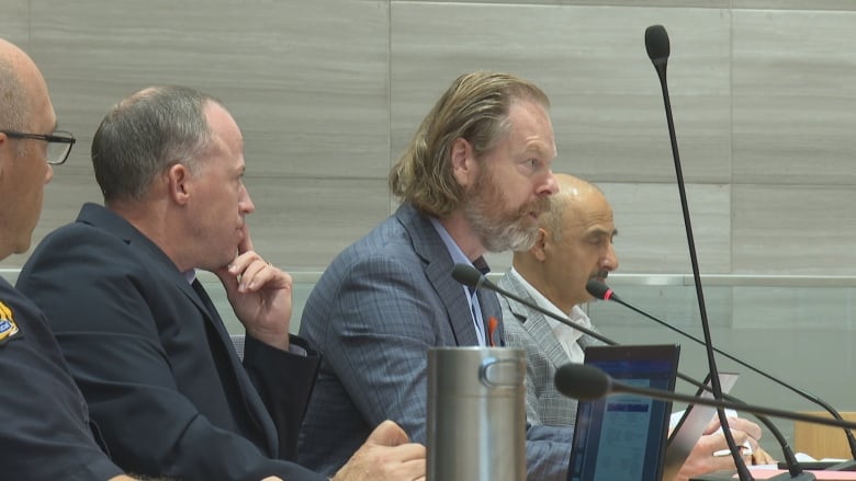 Men in suits at a municipal governance meeting.