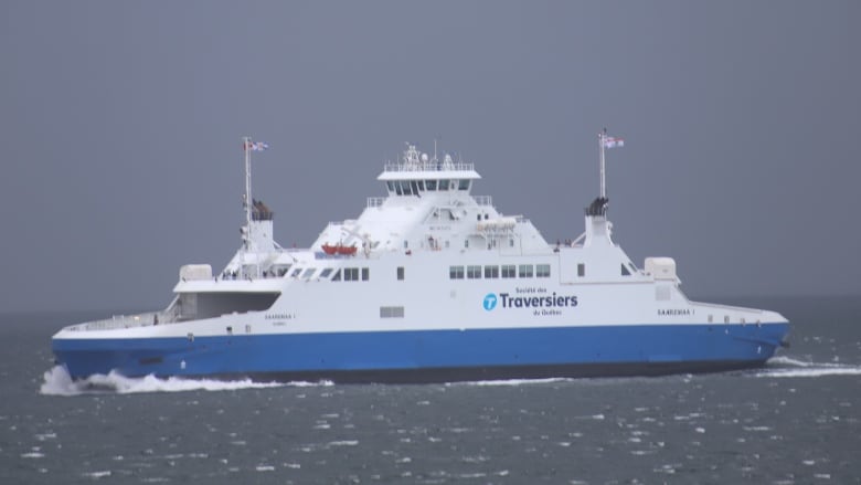 A white and blue ship goes through choppy seas.