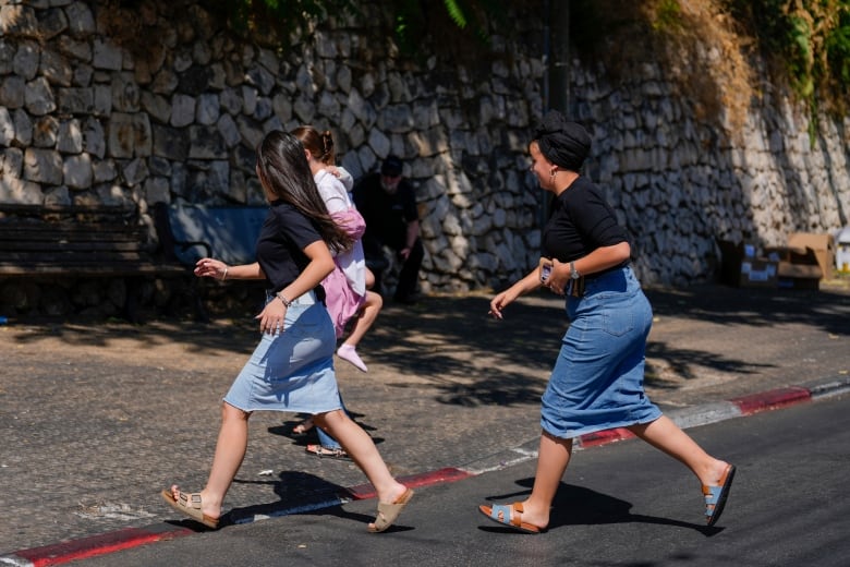 People run to take cover as a siren sounds a warning of incoming rockets fired from Lebanon, in Safed, northern Israel, Thursday, Sept. 26, 2024.