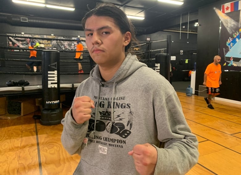 A young boxer raises his fists to pose for a picture.