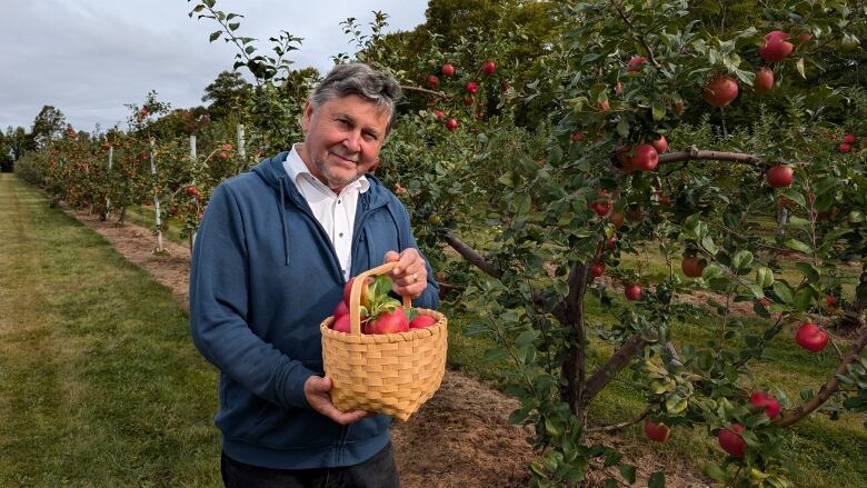 A man stands with a basket of apples 