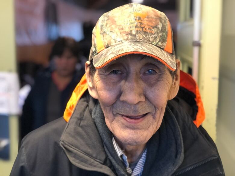 A man wearing a hat stares forward.