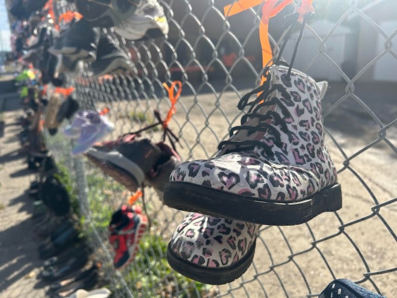 Leopard print shoes tied to a wire wall. 