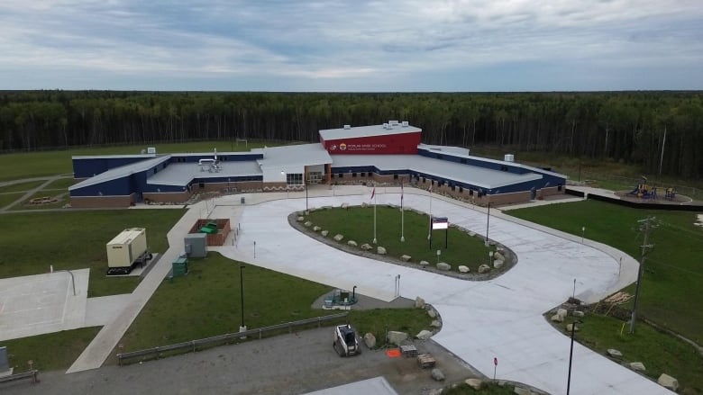 A school surrounded by forest is pictured in an aerial image.