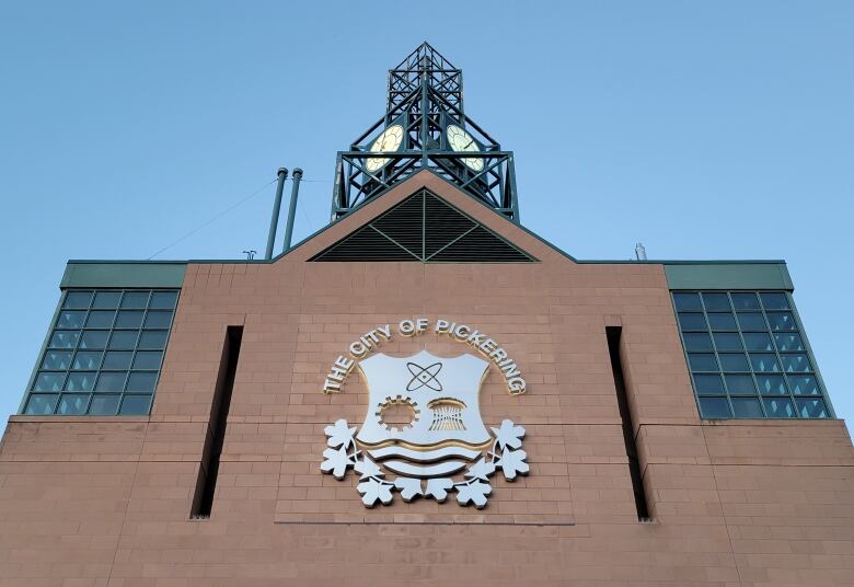 At dusk, the front of the Pickering's City Hall is seen against a blue sky. A clock tower is on top.