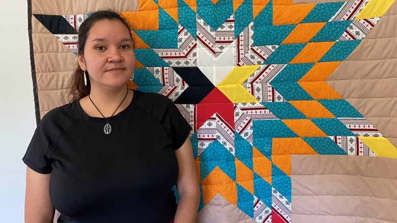 A woman standing in front of Indigenous wall art