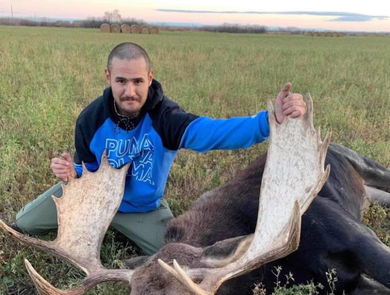 A man next to a dead moose.