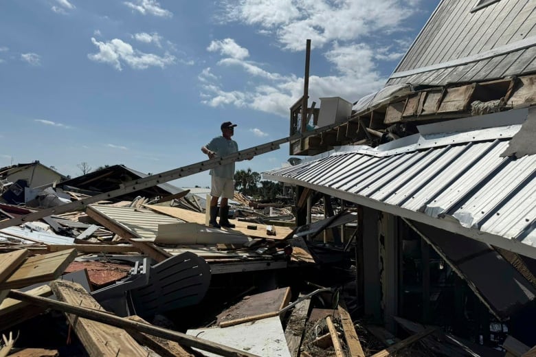 A man stands in the rubble of a home