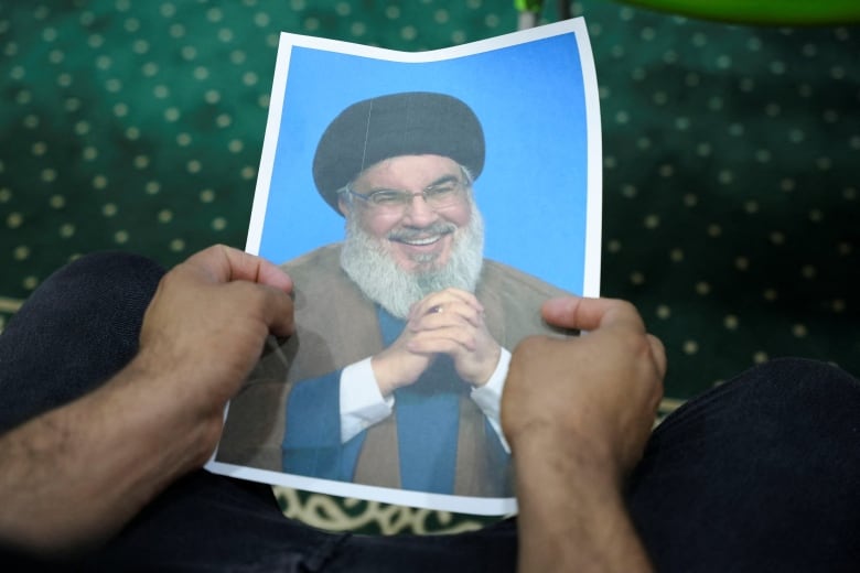 An Iraqi volunteer holds a picture of Lebanon's Hezbollah leader Sayyed Hassan Nasrallah, who has been killed, while registering his name to support Hezbollah, following a call from the Jihad and Construction Movement, a Shi'a Islamist Iraqi political party, in Basra, Iraq, on September 27, 2024. 