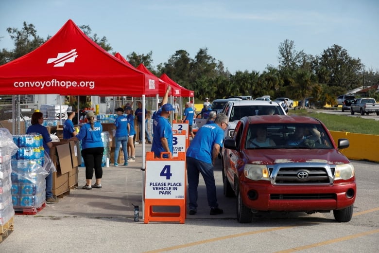 A line of cars receive food and water donations from volunteers.