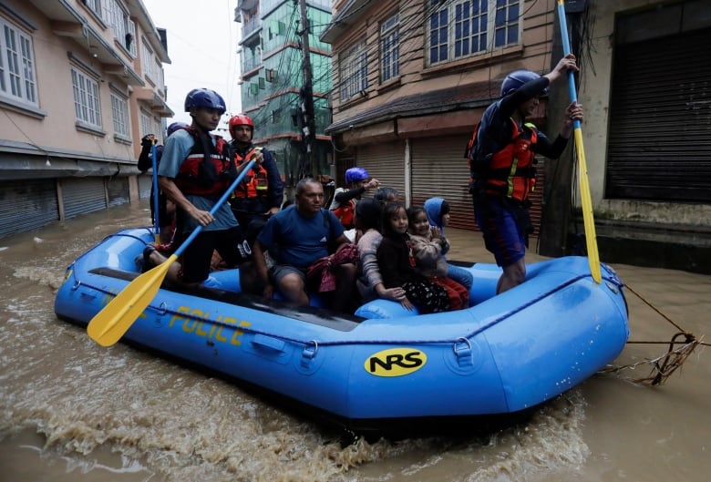 People rescued from a flooding area sit in an inflatable raft.