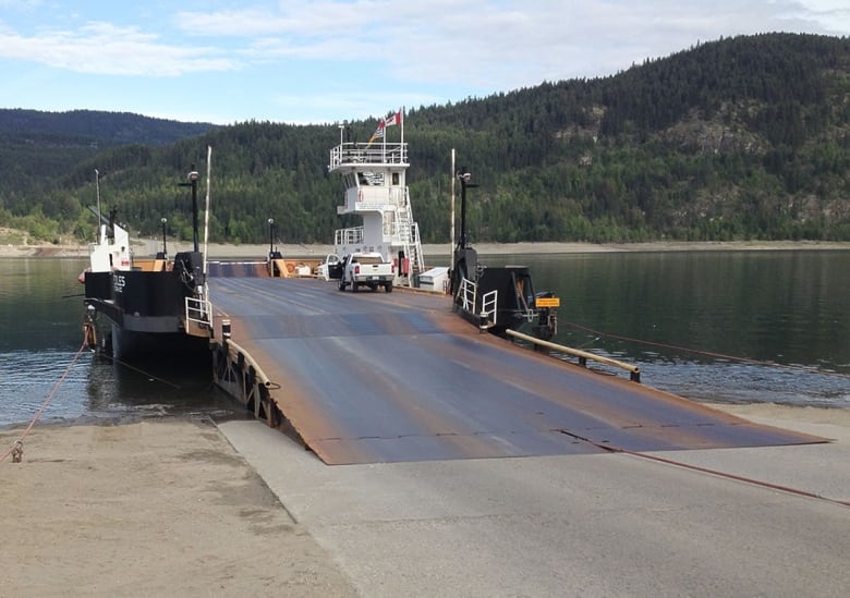 A small car ferry is docked at a lake.