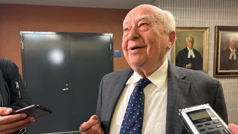 a lawyer speaks to reporters in the courthouse hallway