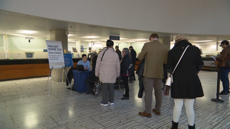 People standing in line waiting to talk to two people sitting at a table.