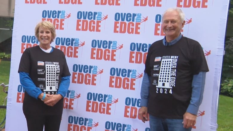 A photo of two people posing in front of a background that says 