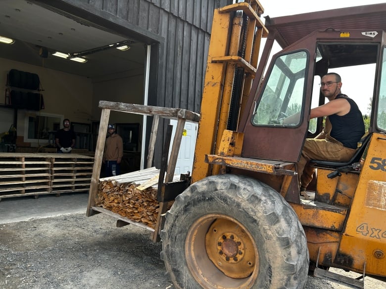 A man driving a forklift, which carries lumber