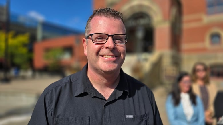 A smiling man in front of a building