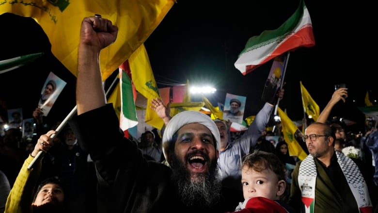 A cleric clenches his fist as he celebrates Iran's missile strike against Israel in an anti-Israeli gathering at Felestin (Palestine) Sq. in Tehran, Iran, Tuesday, Oct. 1, 2024.