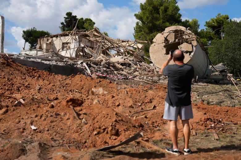 A man takes photos of a destroyed building that was hit in Iran's missile attack in Hod Hasharon, Israel, Wednesday, Oct. 2, 2024.