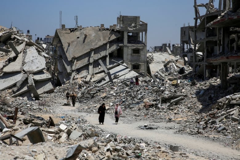 Palestinians walk past the rubble of houses destroyed during the Israeli military offensive, amid Israel-Hamas conflict, in Khan Younis in the southern Gaza Strip