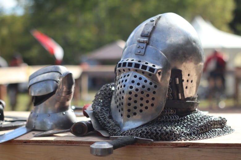 a metal helmet and gauntlets sit on a wood ledge 